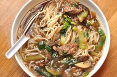 a bowl of beef noodle soup on a wooden table