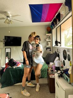 two girls standing in a bedroom looking at their cell phones