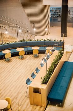 an empty seating area with blue seats and plants on the bench at the center of the room