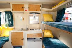 the interior of a small camper with bunk beds and blue curtains on the windows