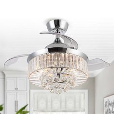 a chrome ceiling fan with crystal chandelier in a white living room, lighting up