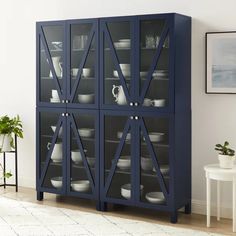 a blue china cabinet with glass doors and plates on the bottom, in a living room