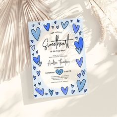 a blue and white card with hearts on it next to some palm fronds