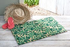 a pair of flip flops sitting on top of a mat next to a straw hat