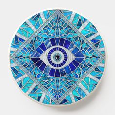 a blue and white plate with an evil eye design on the front, made out of stained glass