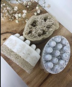 three soaps are sitting on a wooden table next to some plants and flowers in vases