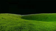 the green grass is growing on top of the hill and in the distance, there is a black sky