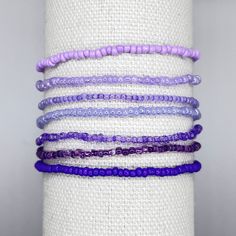 several bracelets are stacked on top of each other in purple and lilac colors