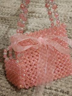 a small pink bag with a bow on the front and beaded details around it