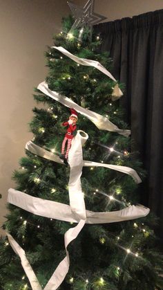 a christmas tree decorated with white ribbon and lights