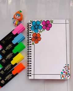 a notebook with markers and a doll next to it