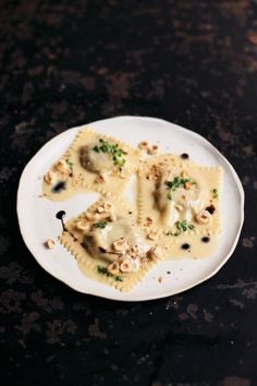 a white plate topped with ravioli covered in sauce