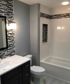 a white toilet sitting under a bathroom mirror next to a sink and bathtub in a bathroom