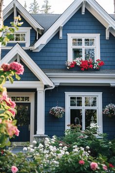 a blue house with flowers in the window boxes