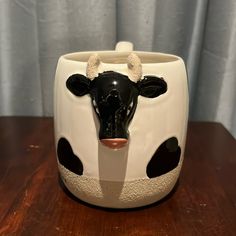 a black and white cow's head is shown in this ceramic container on a wooden table