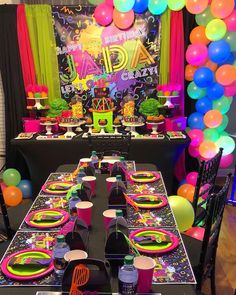 a party table set up with neon colored balloons