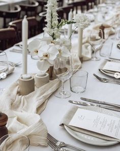 the table is set with white flowers and silverware