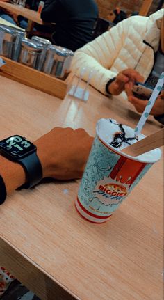 an apple watch sitting on top of a wooden table next to a cup of coffee