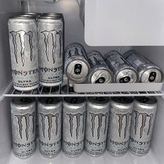 several cans of monster energy drink in an open refrigerator