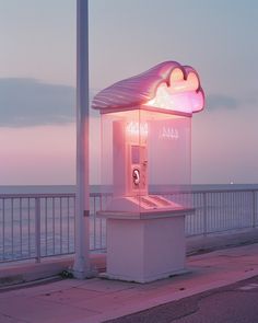 a phone booth sitting on the side of a road next to the ocean at dusk