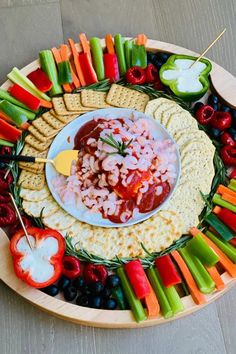 a platter filled with crackers, vegetables and dip