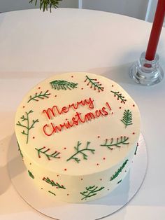 a white cake sitting on top of a table covered in frosting and christmas decorations