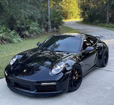 the black sports car is parked on the side of the road in front of some trees