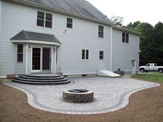 a large white house with a patio and steps leading to the front door that lead into the back yard