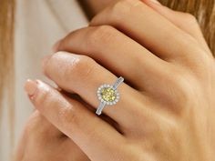 This Fancy Yellow Oval Diamond Halo Engagement Ring is made with an fancy yellow oval solitaire diamond set in a four-prong setting, surrounded by a halo of round diamonds all set on a pave band with round cut diamonds.Details: - Made to Order- Focal Diamond Weight: 1.00 CT, 1.25 CT, 1.50 CT, 1.75 CT, 2.00 CT, 2.50 CT, 3.00 CT- Accent Diamond Weight: 0.47 CT - 0.60 CT (Carat weight varies based on chosen Focal Diamond) - Diamond Type: Lab Grown Diamond (CVD, HPHT)- Focal Diamond Cut: Oval- Accent Diamond Cut: Round- Diamond Clarity: VS - Focal Diamond Color: Fancy Yellow- Accent Diamond Color: Colorless (DEF)- Setting Type: Prong and Pave- Band Thickness: 1.70 MM- Band Width: 2.00 MM- Metal Type: 14K Solid Gold,18K Solid Gold- Choice of Gold Color: Yellow Gold, White Gold, Rose Gold- Jewel Yellow Diamond Ring With Halo, Yellow Diamond Ring With Halo And Round Cut, Yellow Diamond Ring With Halo Setting And Round Cut, Yellow Halo Design Rings, Fine Jewelry Yellow Diamond Ring With Halo Design, Yellow Diamond Rings With Halo Design, Yellow Halo Rings Fine Jewelry, Yellow Fine Jewelry Rings With Halo Design, Yellow Diamond Ring With Pave Setting