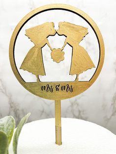 a wedding cake topper with two bride and groom silhouettes in gold on a white cake