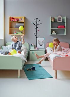 two children playing with yellow balloons in their bedroom, one boy is sitting on the bed