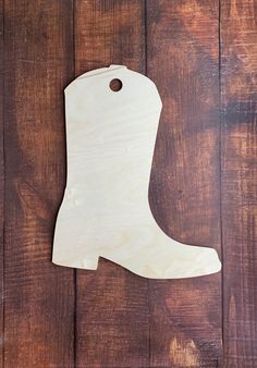 a wooden ornament with a boot on it sitting on a wood floor next to a pair of scissors