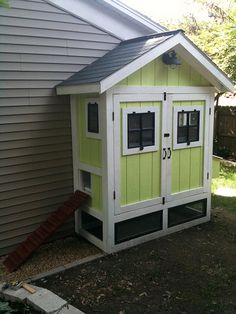 a small green and white shed next to a house