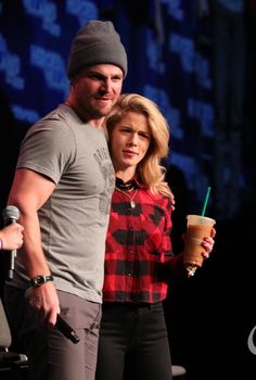 a man and woman standing next to each other with drinks in their hands on stage