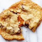 a close up of a cookie on a marble surface with one bite missing from it