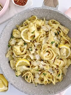 a bowl full of pasta with lemons and parmesan cheese on the side