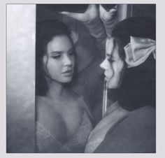 two women looking at each other in front of a mirror with one woman's face partially covered