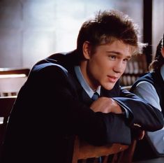 two young men sitting at a table with their arms crossed