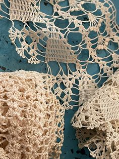 crocheted doily on a blue surface with white laces hanging from it