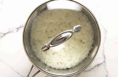 rice is being cooked in a pot with a ladle on the stove top, ready to cook