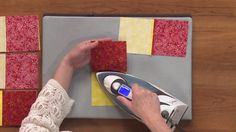 a person using a iron to press quilt block seams