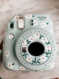 an instax camera with flowers painted on it