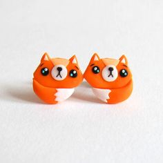 two orange and white cat earrings with blue eyes on top of each other, sitting next to each other