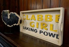 a wooden sign sitting on top of a shelf next to a piece of tree trunk