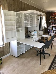 a room with a desk, shelves and chairs in it