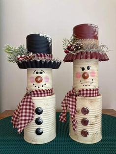 two snowmen made out of tin cans sitting on top of a table