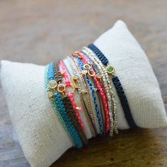 a stack of bracelets sitting on top of a white cloth covered pillow in front of a wooden table