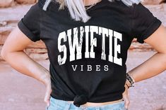 a woman with blonde hair wearing a black shirt that says swietie vibes