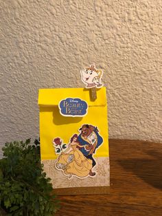 a yellow bag sitting on top of a wooden table next to a potted plant