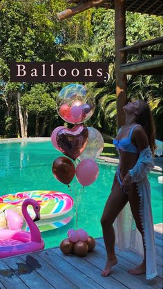 a woman standing next to a pool filled with balloons